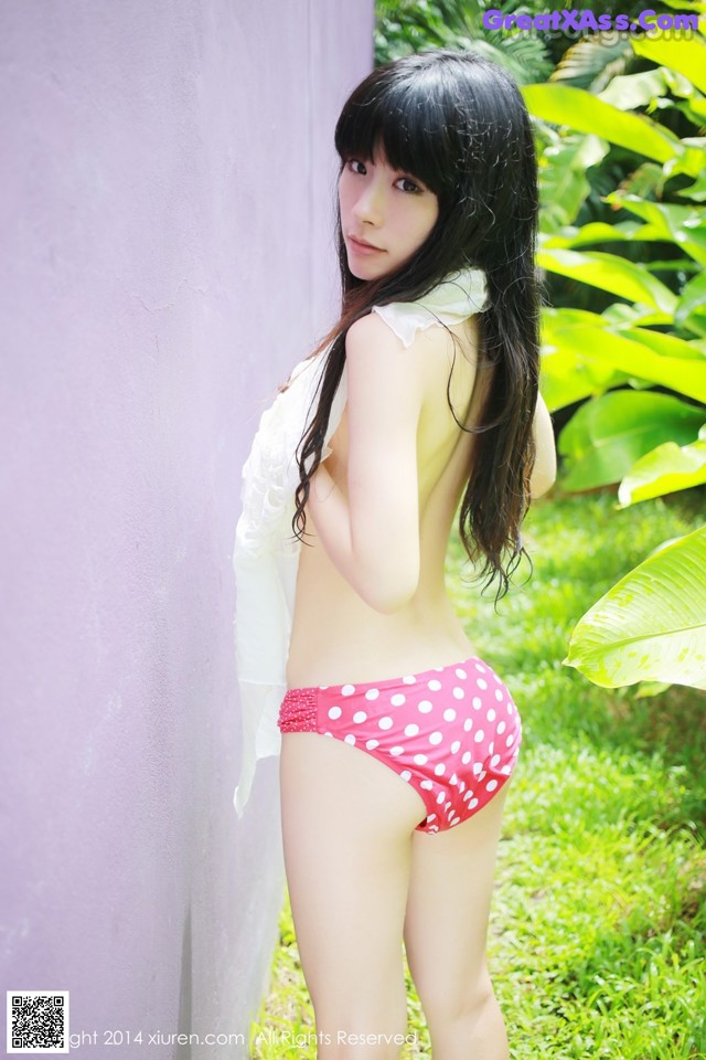 A woman in a pink and white polka dot bikini posing for a picture.