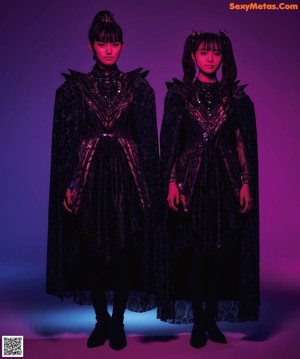 Two young women dressed in black standing next to each other.