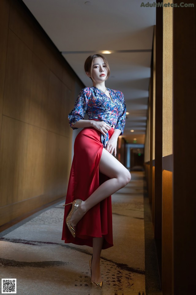 A woman in a red skirt is posing for a picture.