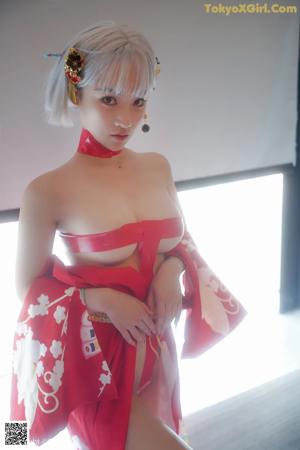 A woman in a red kimono sitting in a bathtub.