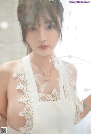 A woman in a white lingerie is posing for the camera.