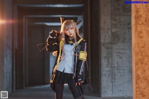 A woman in a black and yellow outfit holding a rifle.