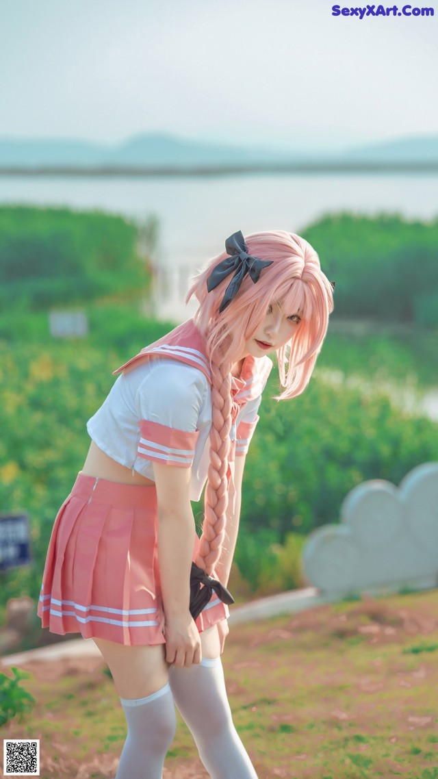 A woman in a pink and white outfit is posing for a picture.