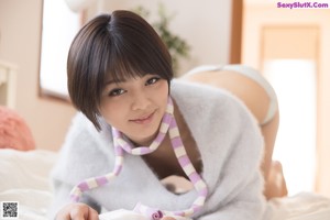 A woman in a white sweater is posing on a bed.