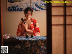 A woman in a red kimono sitting on a tatami mat.