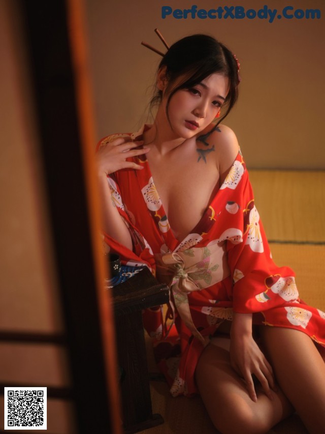 A woman in a red kimono sitting on the floor.