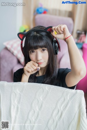 A woman sitting on a bed wearing a cat ears headband.