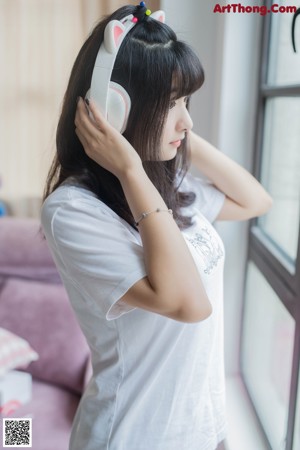 A young woman wearing a pair of cat ears and headphones.