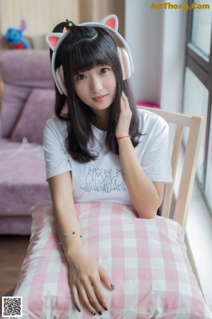 A woman sitting on a bed wearing a pair of headphones.