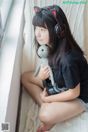 A young woman wearing a cat ears headband and headphones.