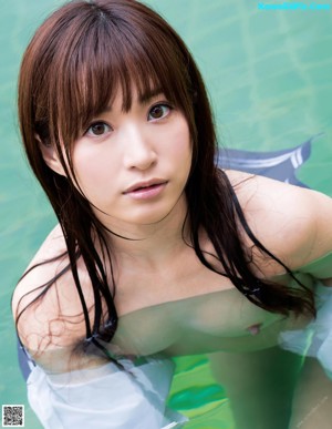 A naked asian woman sitting on the edge of a pool.