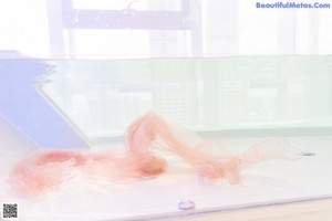 A woman sitting on top of a bathtub next to a mirror.