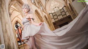 A woman in a white dress playing a violin.