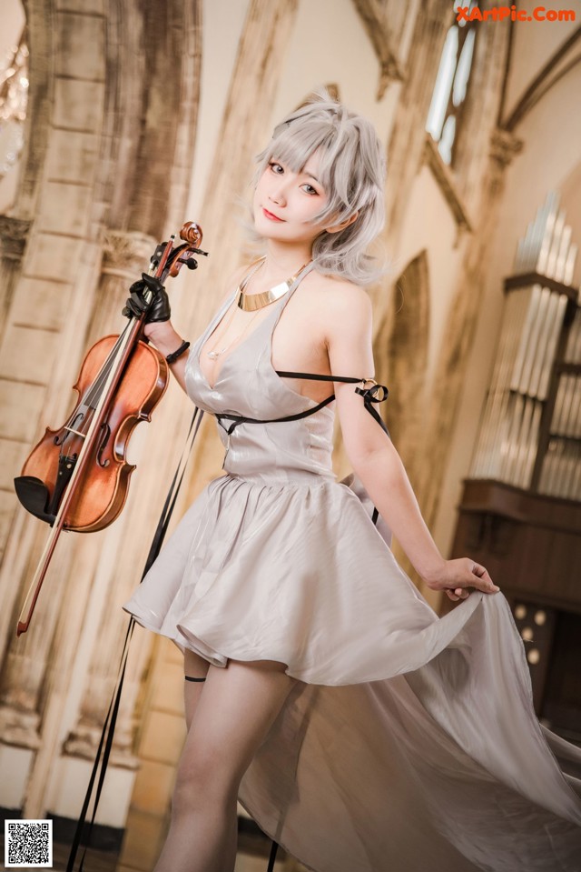 A woman in a white dress holding a violin.