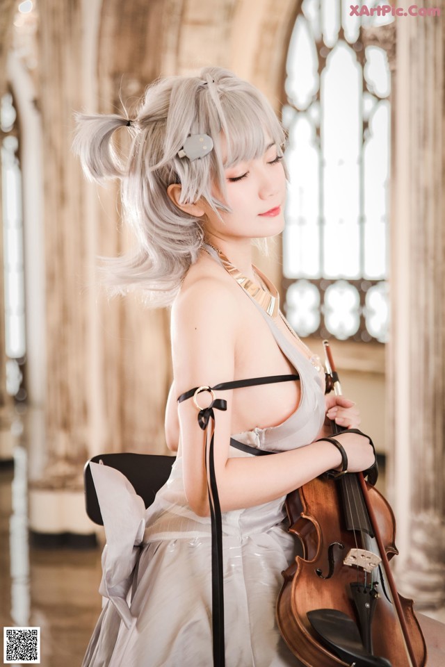 A woman in a white dress playing a violin.