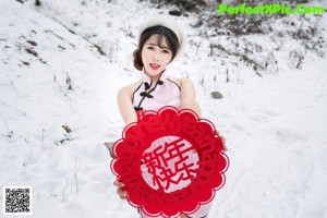 A woman in a pink dress holding a red paper fan.