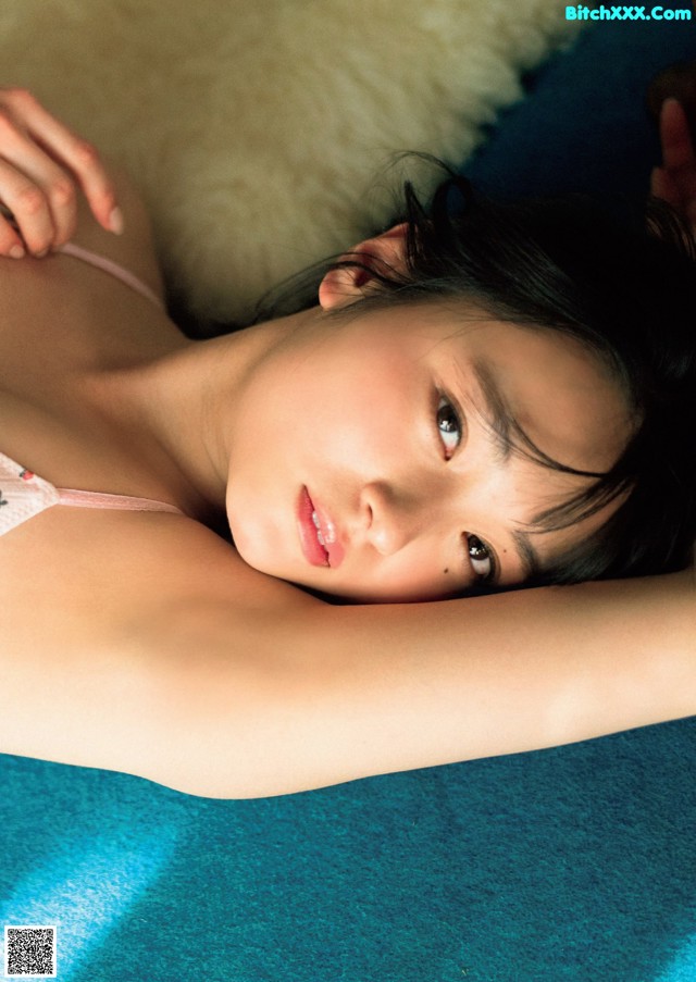 A woman laying on top of a bed next to a pillow.