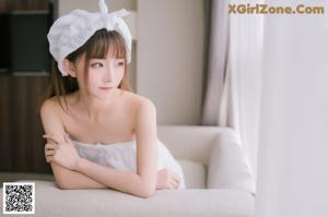 A woman in a white dress laying on a couch.