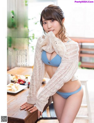 A woman in a red bra top and blue panties eating a strawberry.