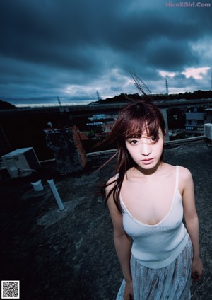 A woman in a white tank top and skirt posing for a picture.