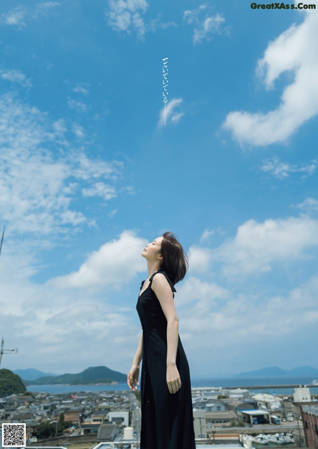 A woman in a black dress standing on top of a building.