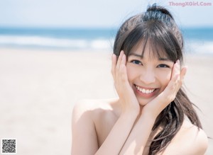 A woman in a white dress standing on a beach.