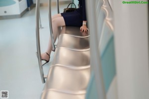 A woman in a blue dress sitting on a glass table.