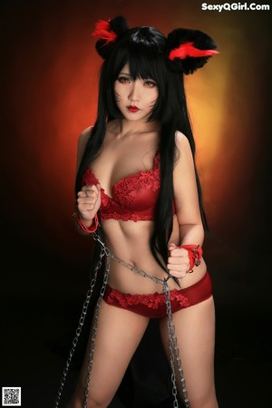 A woman in a red lingerie is tied up with chains.