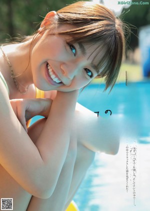 A woman in a bikini sitting on a wooden deck.