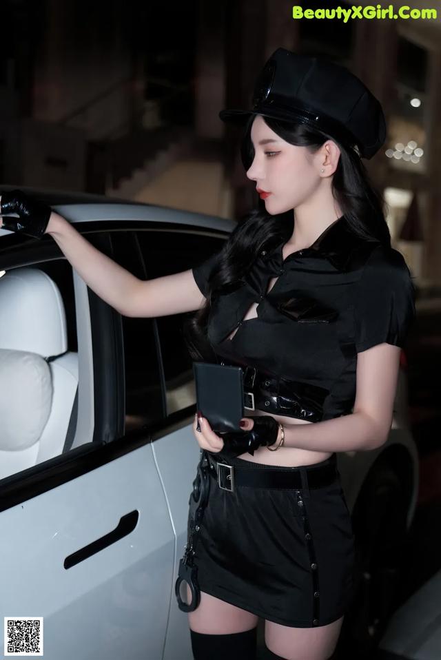 A woman dressed as a police officer standing next to a car.