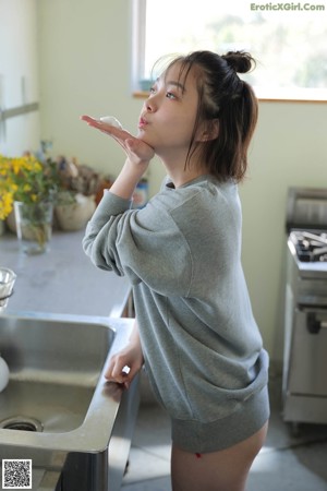 A woman standing in a kitchen next to a sink.