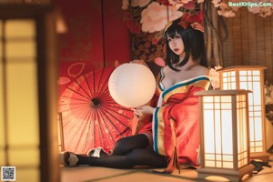 A woman in a red and black kimono sitting on the floor.