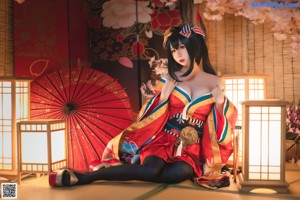 A woman in a red and blue kimono sitting on the floor.