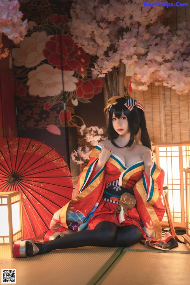 A woman in a kimono sitting on the floor with an umbrella.