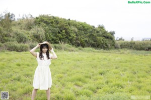 A naked asian woman wearing a straw hat posing for the camera.