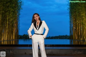 A woman in a white suit sitting on the floor.