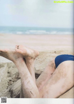 A woman in a blue bikini laying on the beach.