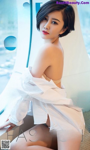 A woman in a white dress sitting on a couch.