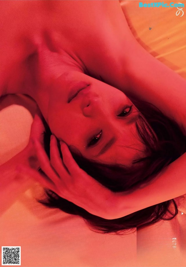 A woman laying on top of a bed next to a red light.