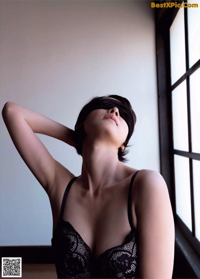 A woman in a black lingerie with a blindfold on her face.