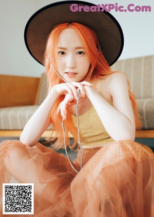 A woman with bright orange hair laying on a bed.