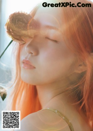 A woman with bright orange hair laying on a bed.
